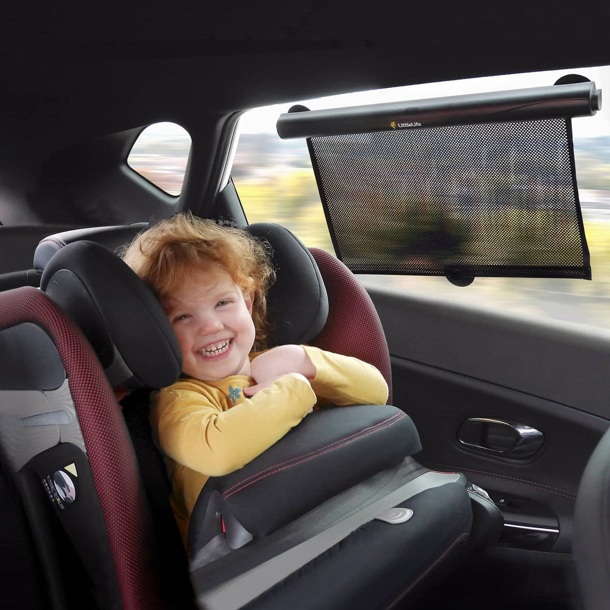 Kind sitzt im Autositz mit Sonnenschutz und Autozubehör für sichere und komfortable Autofahrten