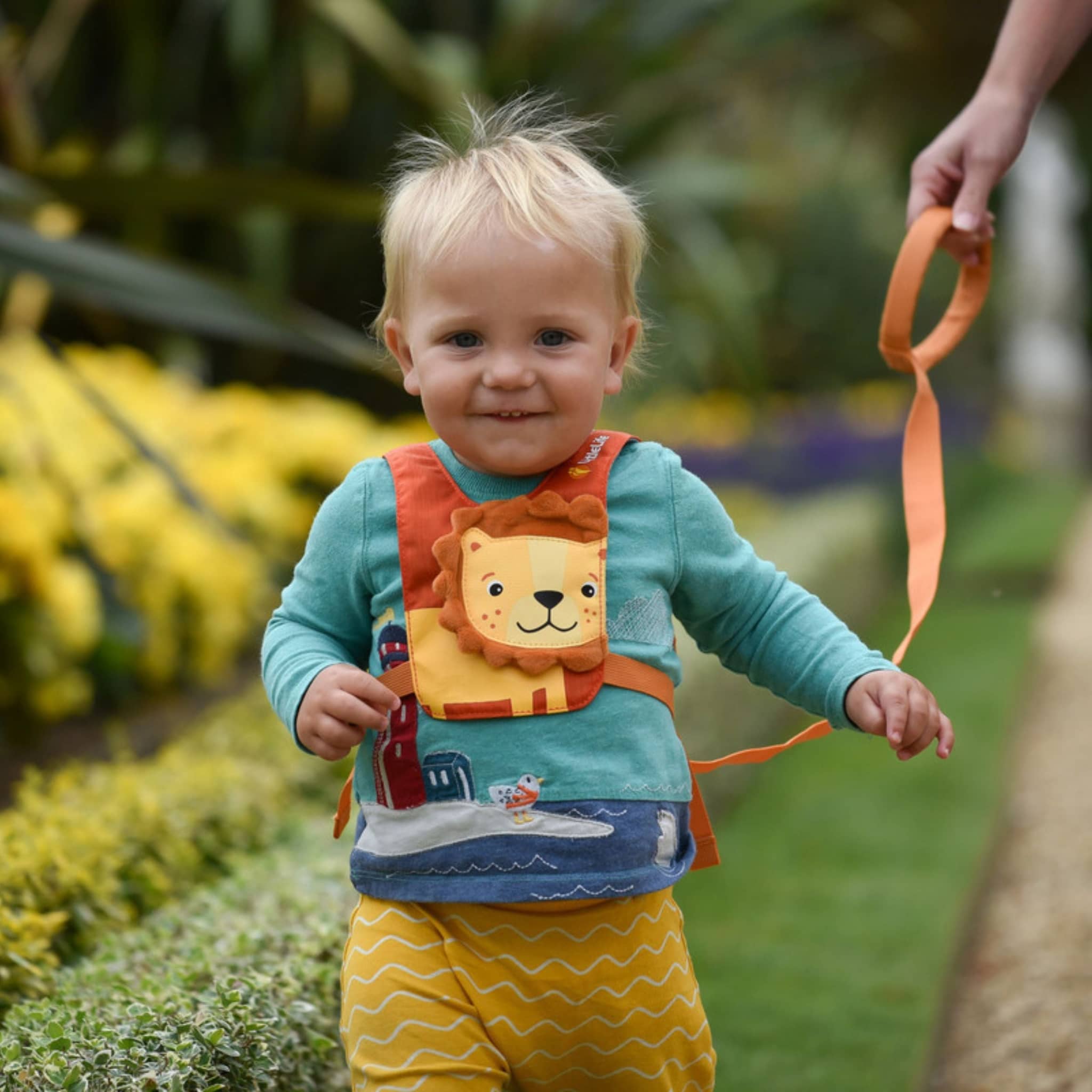 Kleines Kind trägt Sicherheitsgurt Löwe als Reisezubehör für Kinder im Garten