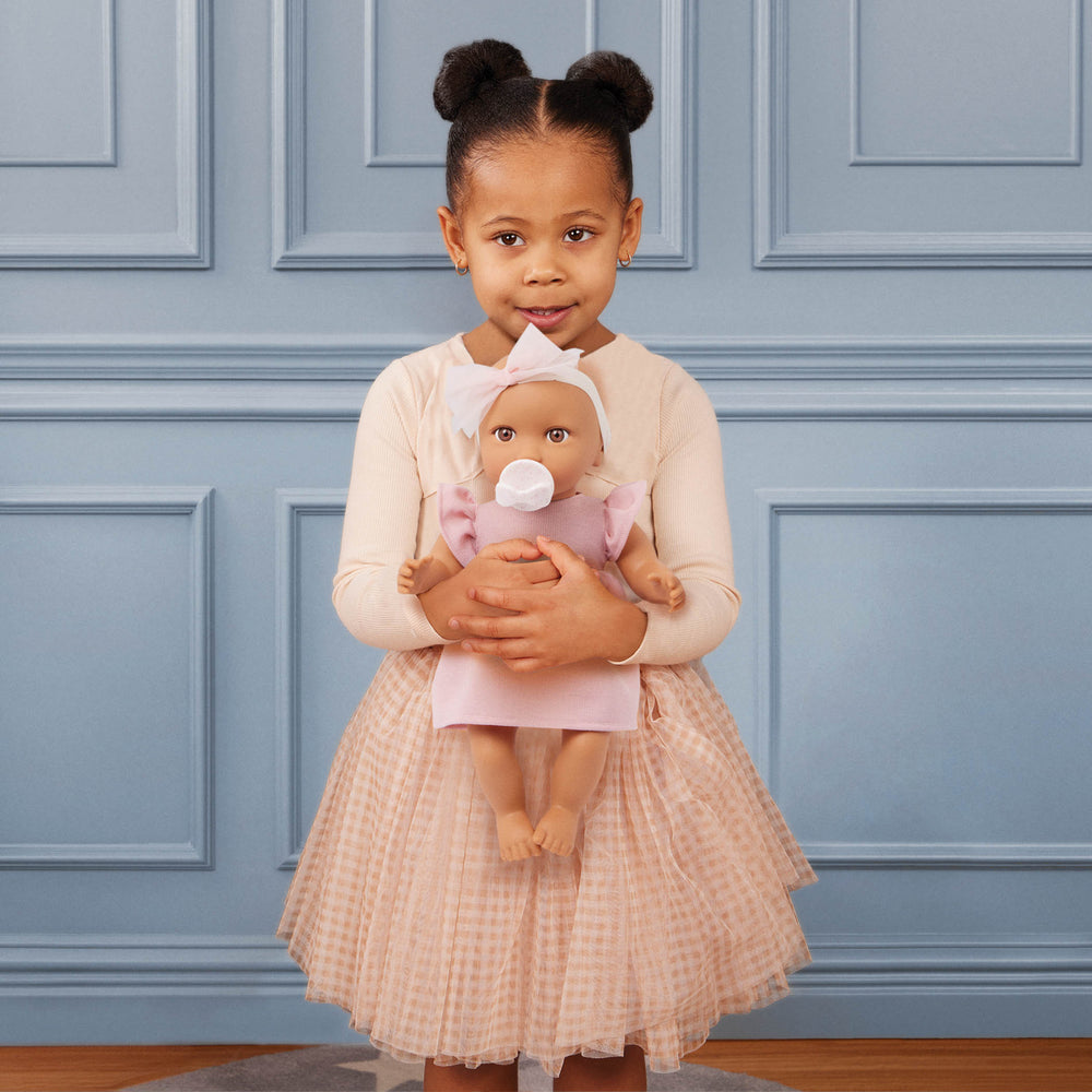 Babypuppe mit Schnuller im Kleid mit Stirnband
