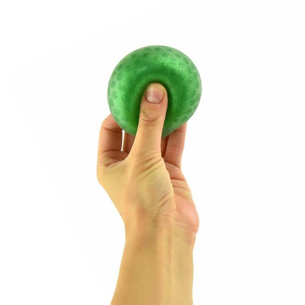 Hand drückt einen grünen Glitzer-Knautschball, dahinter ein Display Glitter Squeeze Ball