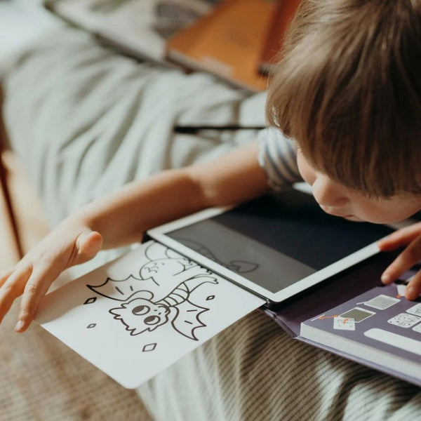 Ein Kind malt mit dem Grafiktablett Kidydraw Mini – Prinzessinnen auf einem Blatt Papier.