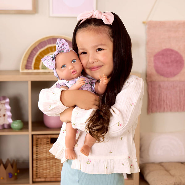 Babypuppe mit Schnuller – in einem Kleidchen mit Blümchenmuster und einem Haarband