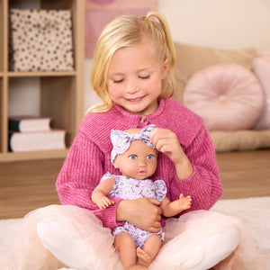 Babypuppe mit Schnuller – in einem Kleidchen mit Blümchenmuster und einem Haarband