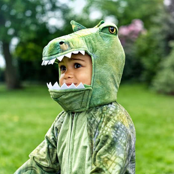 Kind im T-Rex-Overall mit Kapuze und Zähnchen im Garten