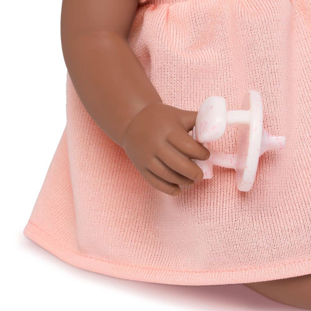 Babypuppe mit Schnuller – in einem orangefarbenen Kleid und mit einem Stirnband