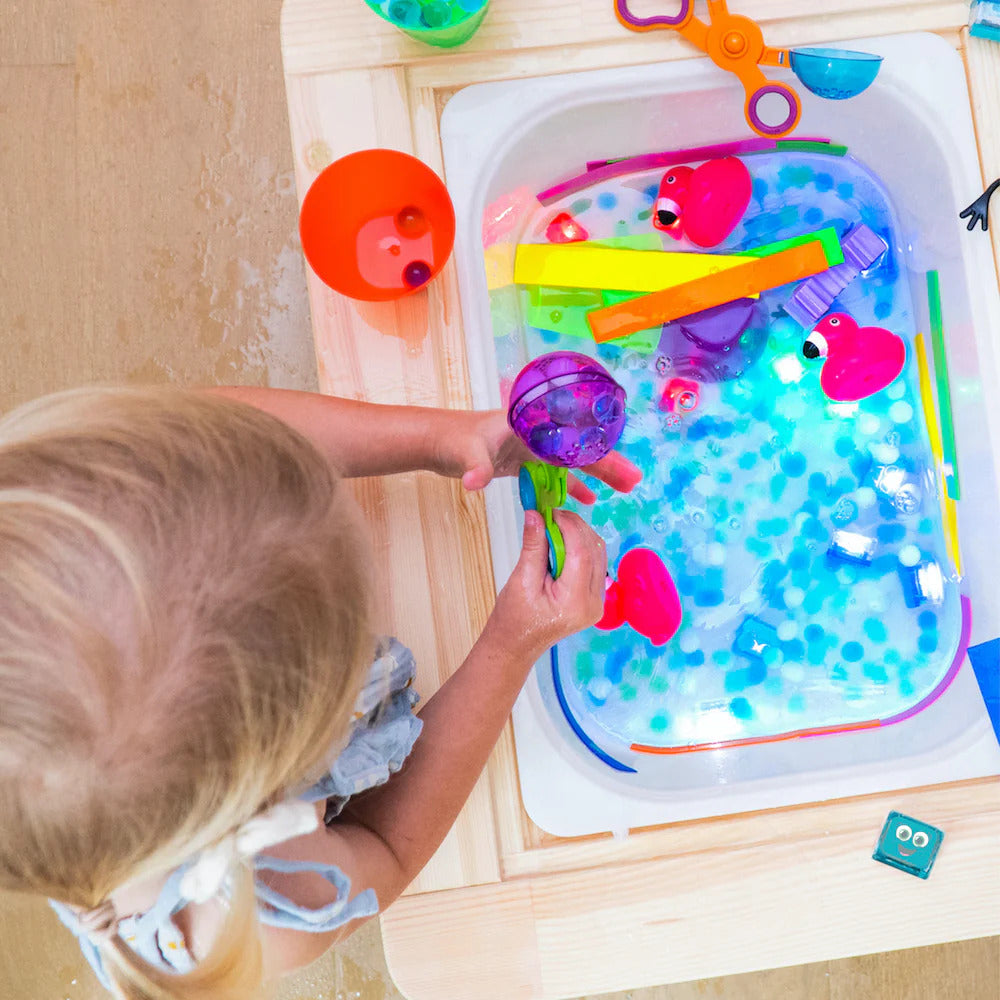 Kind spielt mit Sensorische Würfel, die im Wasser leuchten Pippa – grün im Wasserbad als Badespielzeug von Glo Pals
