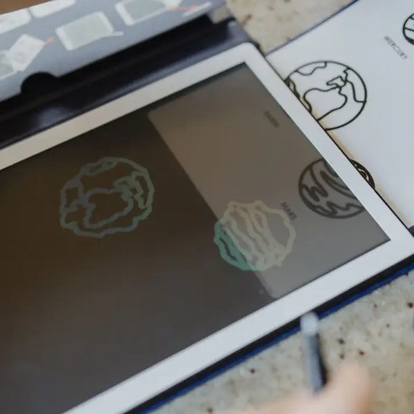 Grafiktablett Kidydraw Mini Galaxie mit Zeichnungen und begleitendem Zubehör auf dem Tisch