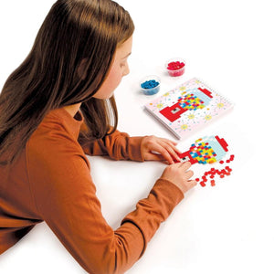 Mädchen, das ein Jixelz Puzzleset kauft, mit bunten Steinen und Anleitungen auf dem Tisch