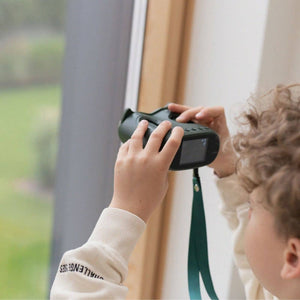 Kind verwendet das Digitalmikroskop KidLupe zur Untersuchung von Objekten durch ein Fenster