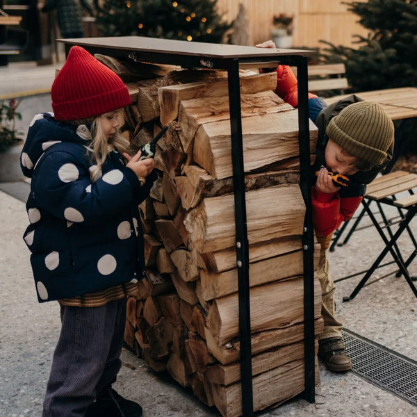 Kinder mit Walkie-Talkie Set beim Spielen hinter einem Holzstapel im Freien