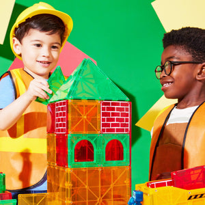 Kinder bauen mit Magnetbausteinen für Kinder ein buntes Gebäude aus MAGNA-TILES