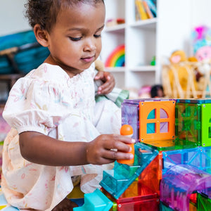 Kind spielt mit MAGNA-TILES Magnetbausteinen Kinder auf einer bunten Struktur