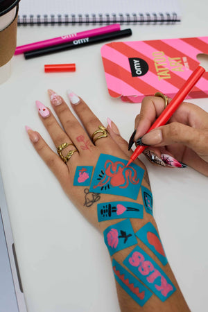 Tattoo Marker Set für Kinder in Verwendung mit bunten Designs auf der Hand einer Person