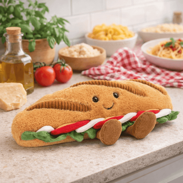 Jellycat Plüsch Baguette Caprese mit freundlichem Gesicht und bunten Details in einer Küche