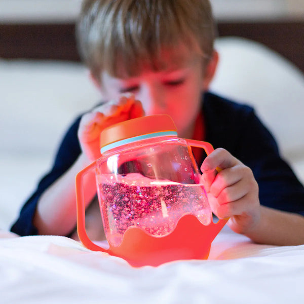 Kind spielt mit dem Sensorik-Glas zum Befüllen mit Wasser – rot von Glo Pals als Zabawka progresywna