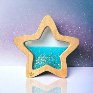 Sensorischer Stern leuchtet im Dunkeln aus Holz mit glitzerndem, blauem Flüssigkeitsinhalt