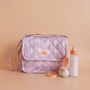 Tasche mit Zubehör für Puppen von Tiny Harlow, lila mit Blumenmuster, inklusive Flasche und Löffel.