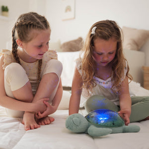 Zwei Mädchen spielen mit der Tranquil Turtle Spieluhr Projektor, die beruhigende Lichter zeigt